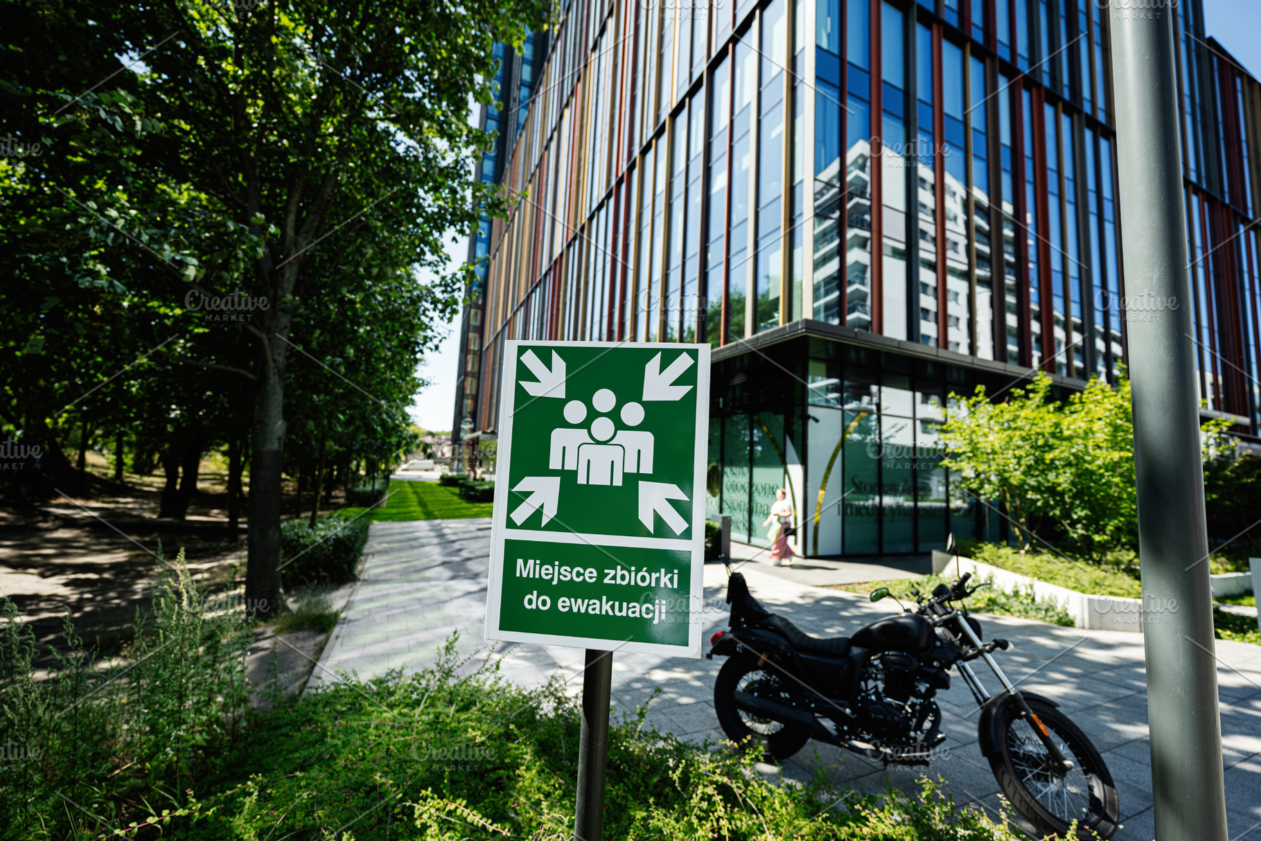 Evacuation assembly point sign near a modern building and motorcycle in Warsaw, a Photo by AS photostudio