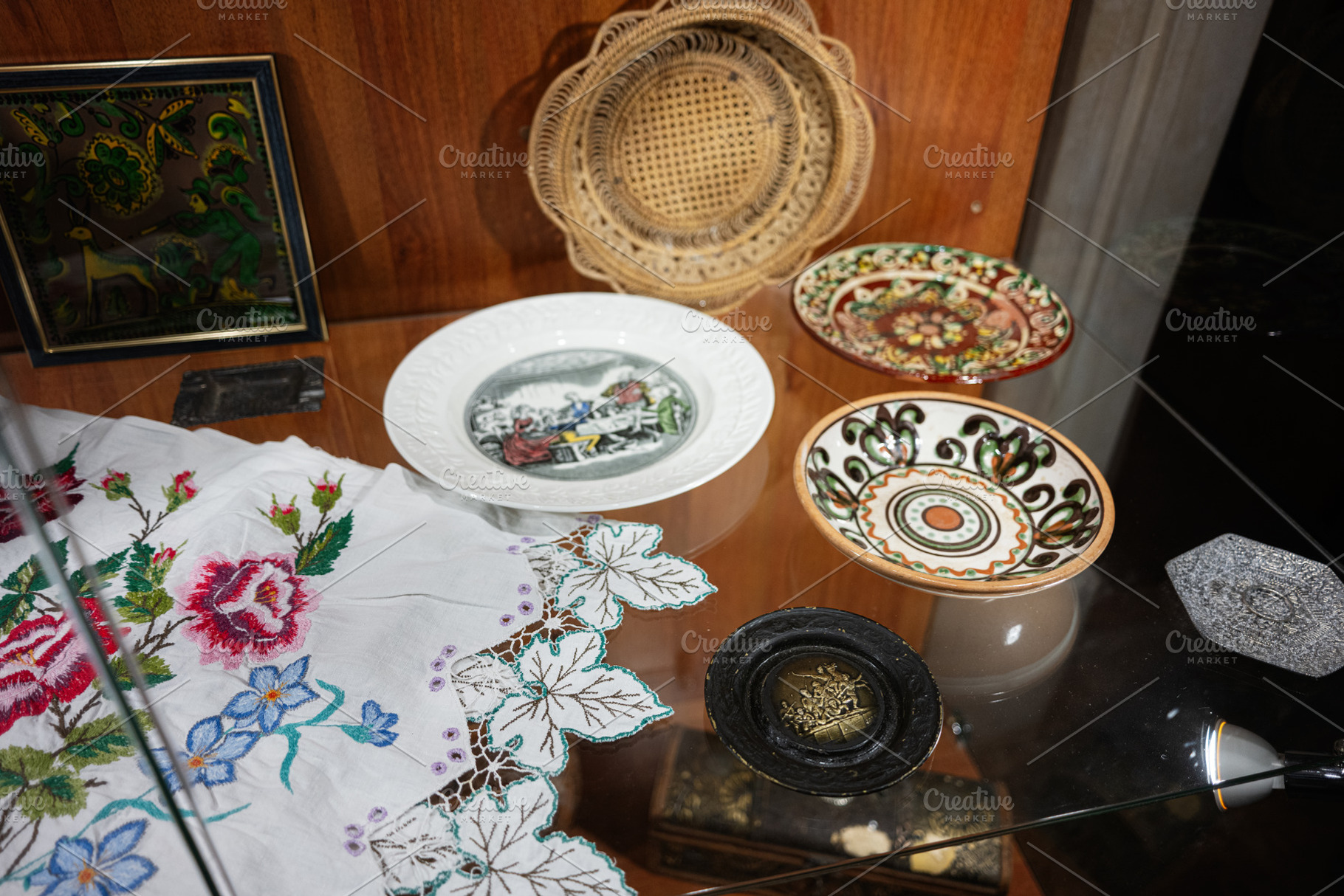 Display of decorative plates and embroidery in a glass front cabinet, a Photo by AS photostudio