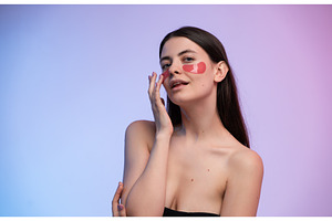 Young woman applying red eye patches, a Health & Medical Photo by volodymyrshtun13795