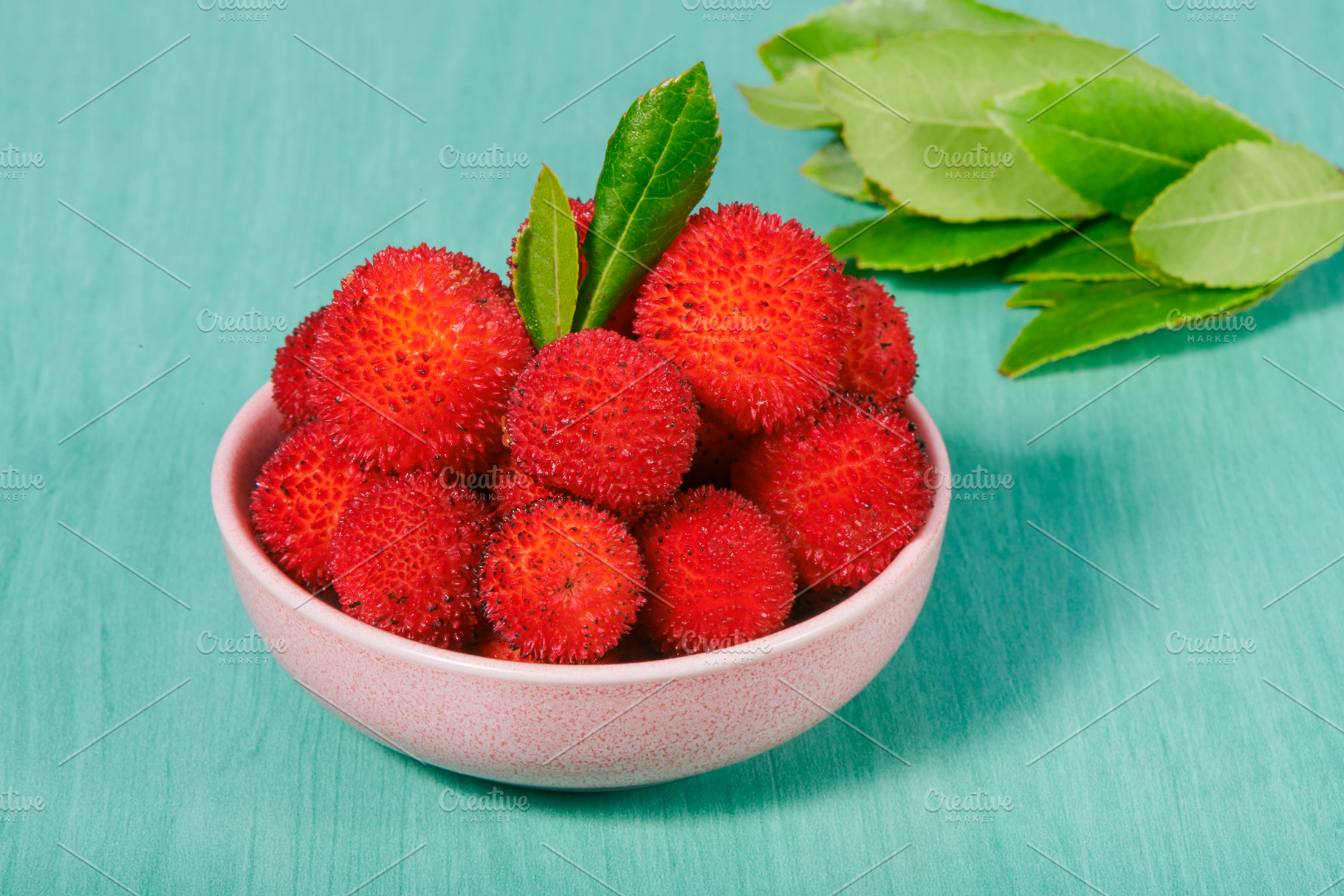 arbutus berries in a small pink bowl on turquoise, a Photo by Nito