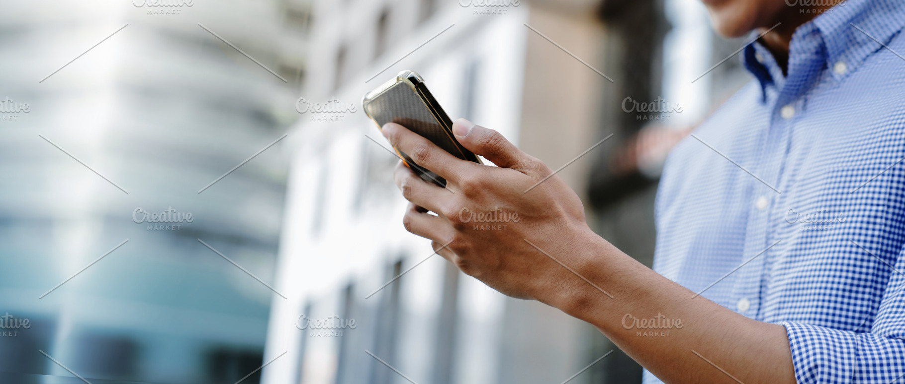 A man using a smartphone in an urban environment, representing m, a Technology Photo by salmon.black