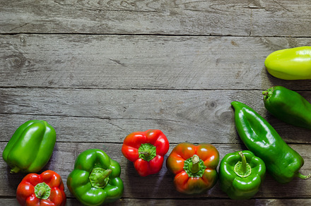 Green and red pepper on wooden background