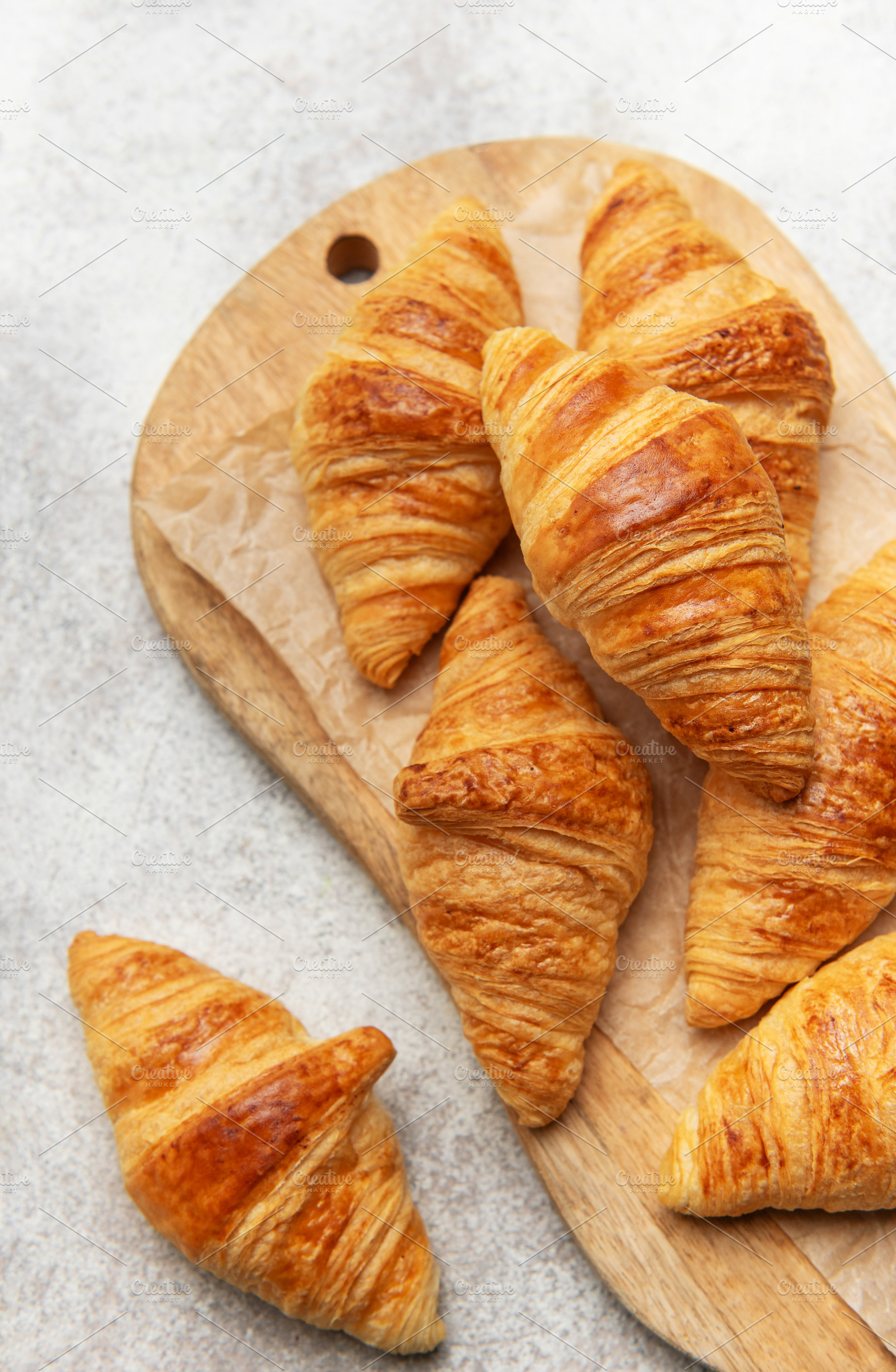 Freshly baked croissants on wooden board, a Food & Drink Photo by Olena Rudo