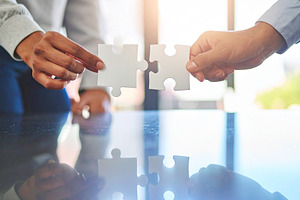 Two professional hand connecting two puzzle pieces on a desk, a Business Photo by DanFLCreativo