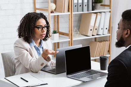 Serious black woman speaking to her male colleague at company office, asking ab, a Photo by Prostock-Studio