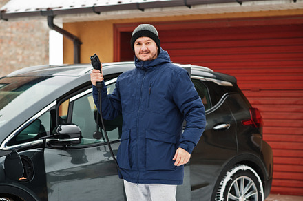 Young man charging his electric car in winter. Eco transport con, a Person Photo by AS photostudio