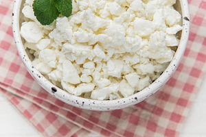 Cottage cheese in bowl with mint leaves on checkered napkin, a Food & Drink Photo by Olena Rudo