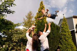 Father tosses laughing son skyward, a Person Photo by Elena Vagengeim