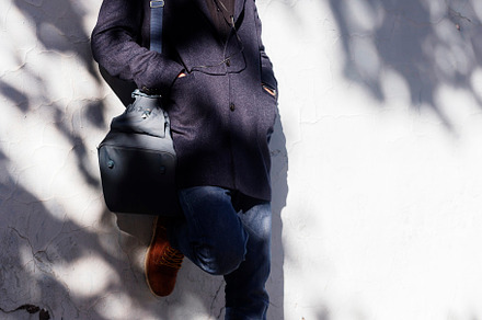 Man leaning on a wall with headphones under dappled sunlight., a Person Photo by RF Images