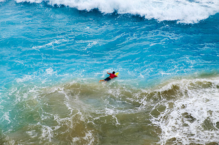 Aerial view of Surfer swimming on a board near huge blue ocean wave in Bali, a Nature Photo by ifnotelse