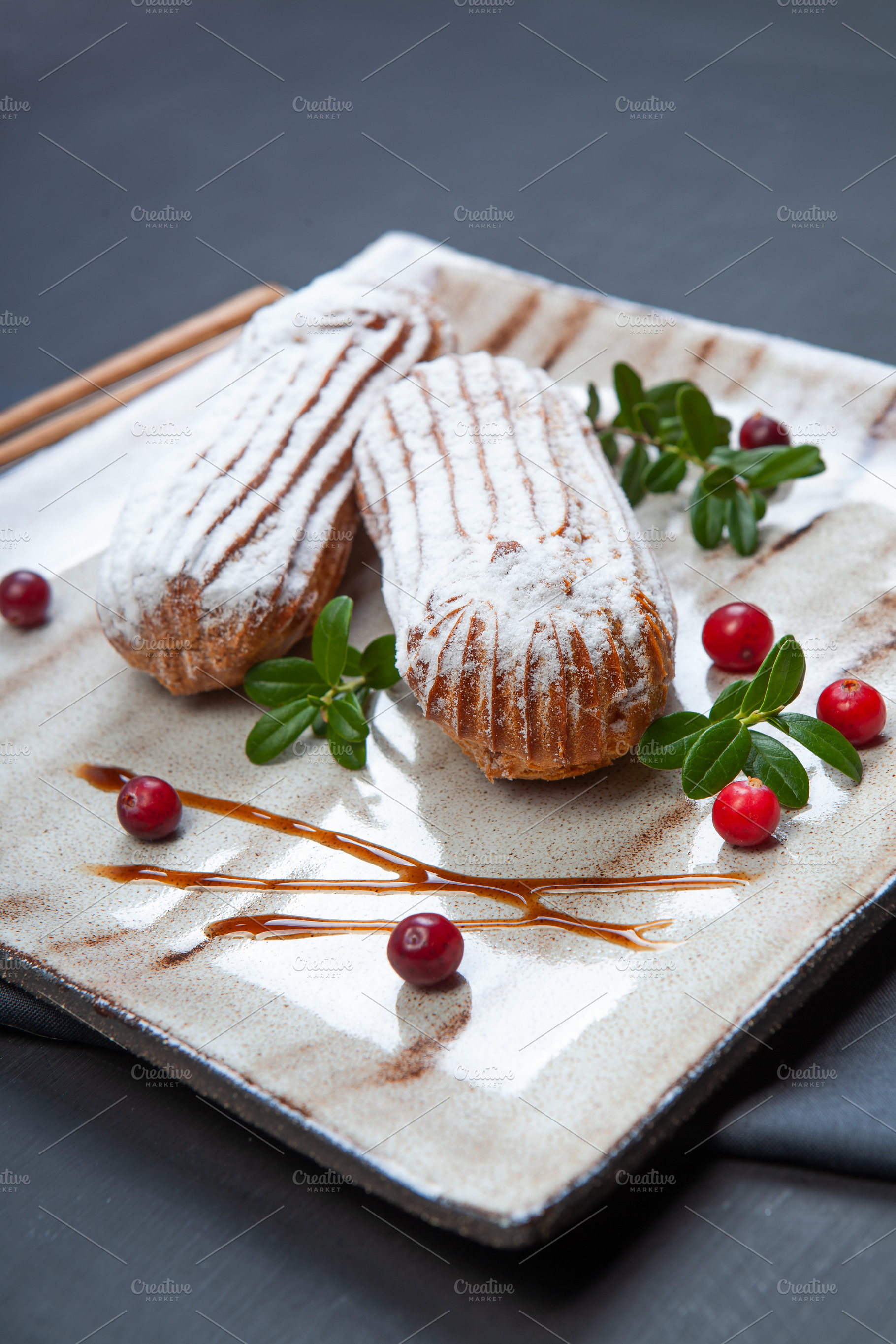 Cream eclairs choux pastries served with fresh cranberries on a, a Food & Drink Photo by eleana