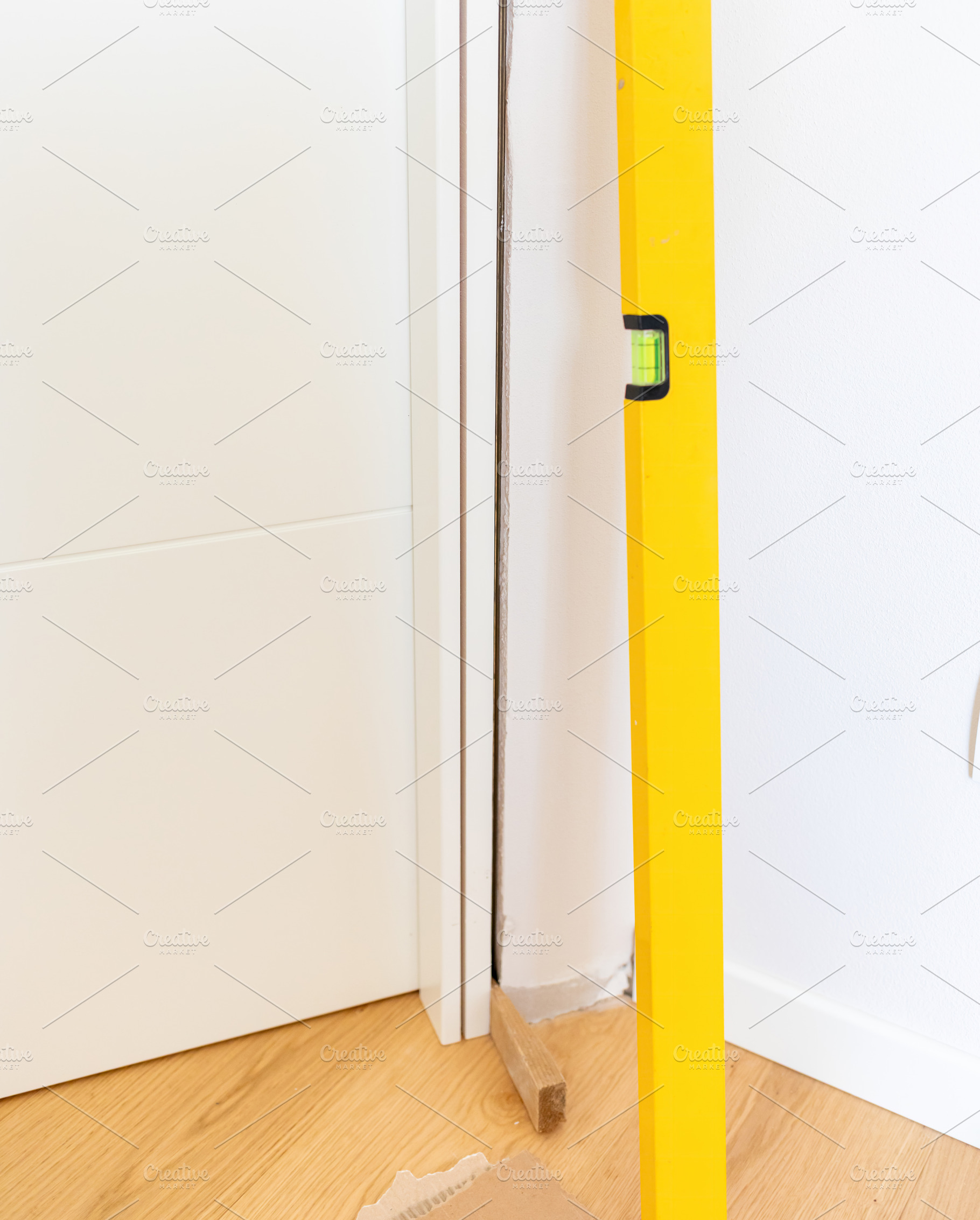 Construction worker using spirit level during door installation, an Architecture Photo by Antonio Gravante Market