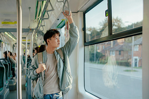Asian teenager riding public transportation in city, a Person Photo by DanFLCreativo