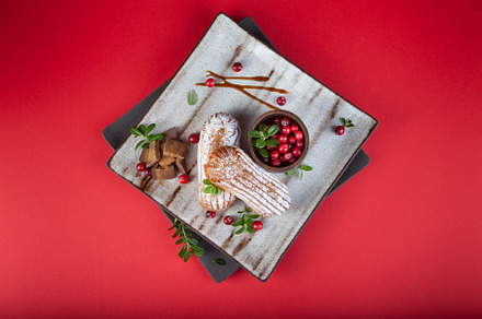 Cream eclairs choux pastries served with fresh cranberries on a