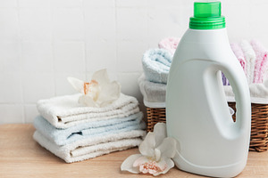 Laundry detergent bottle with fresh clean towels and orchids, an Industrial Photo by Olena Rudo