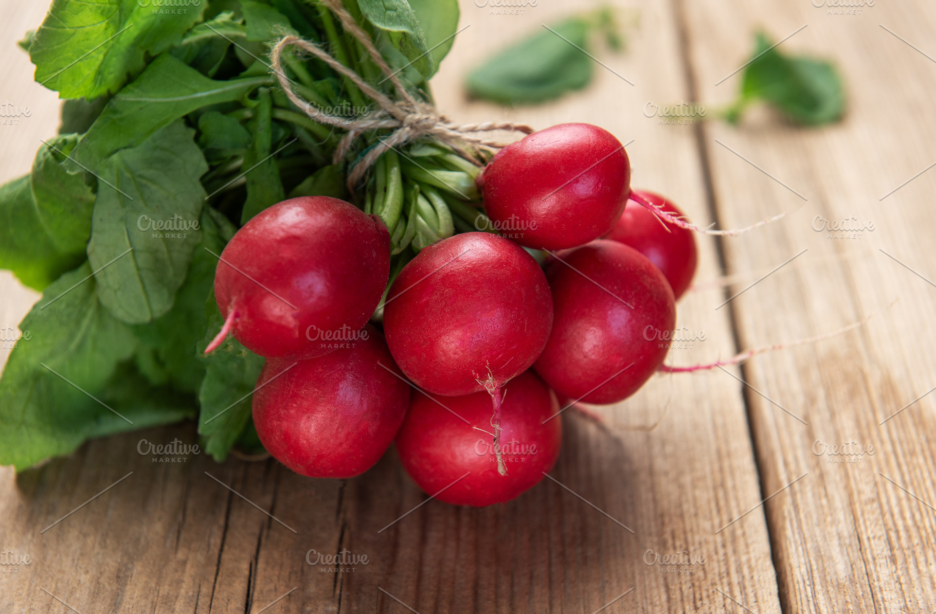Fresh radishes bunch with green leaves on wood table, a Food & Drink Photo by Olena Rudo