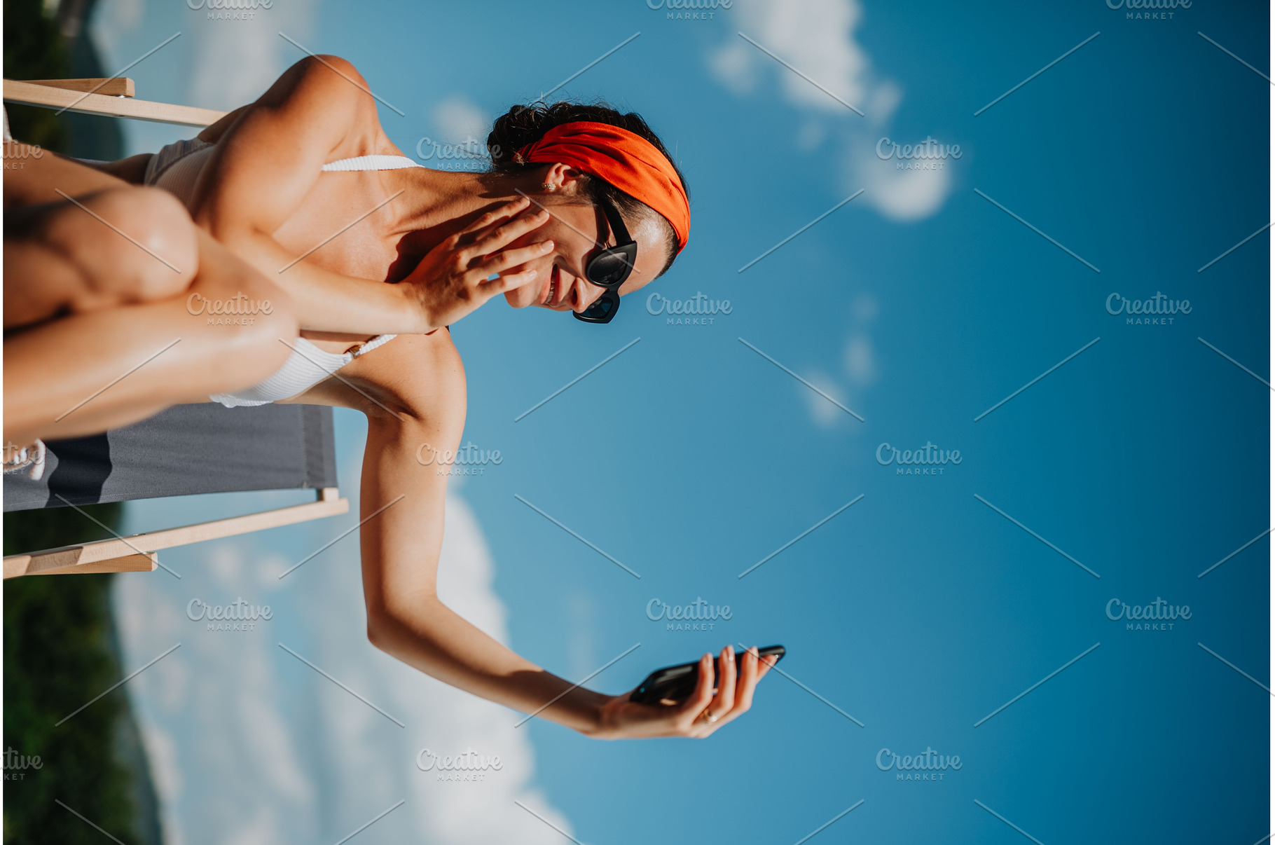 Young woman sitting by swimming pool, a Person Photo by HalfPoint