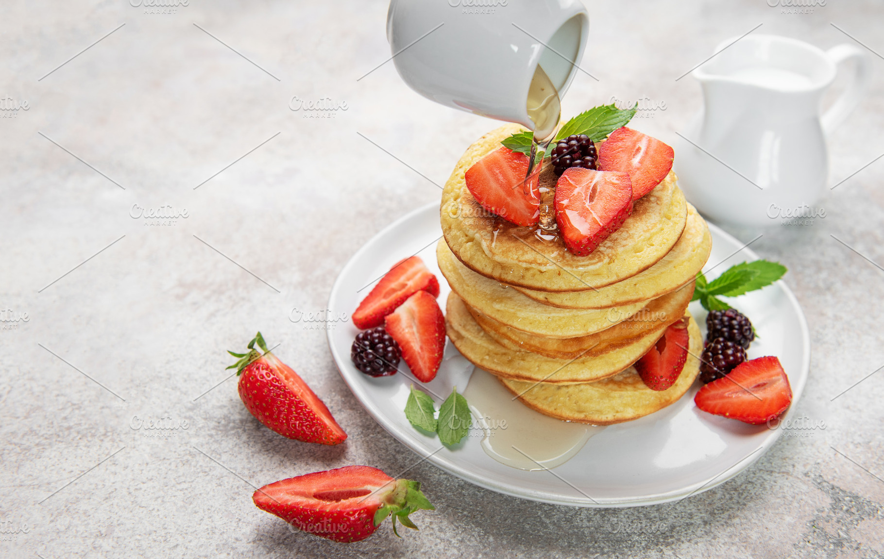 Pancakes with berries and syrup pouring for breakfast, a Food & Drink Photo by Olena Rudo