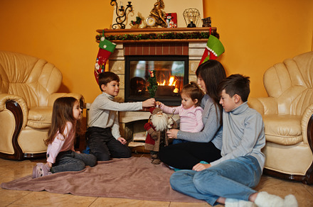 Happy young large family by a fireplace in warm living room on w, a Holiday Photo by AS photostudio