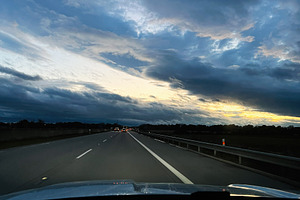 Driving on an empty highway at dusk under dramatic blue skies and glowing horiz, a Photo by AS photostudio