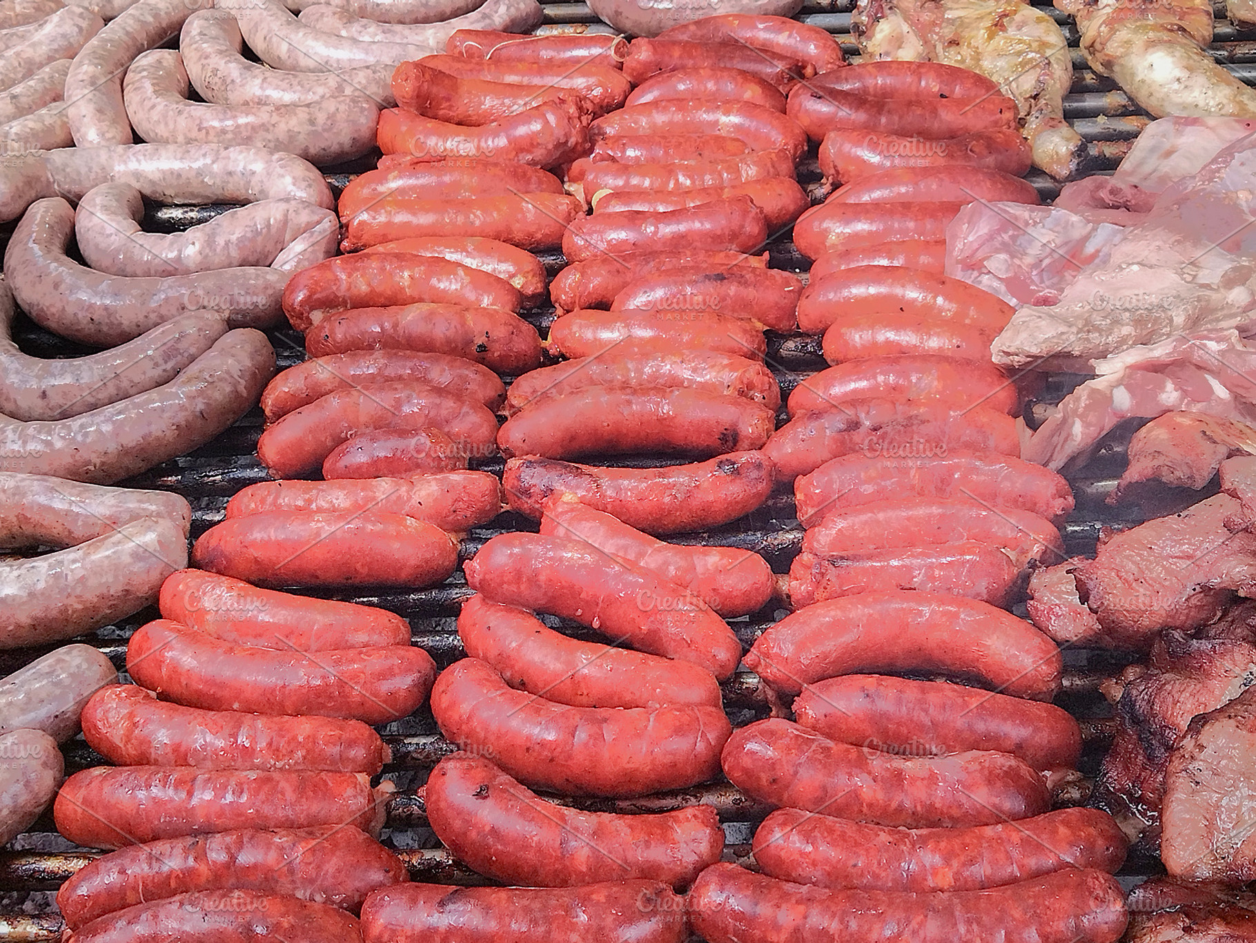 Variety of raw sausages on grill from top view, a Food & Drink Photo by DanFLCreativo