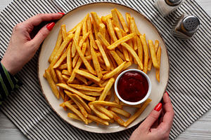 Female hands hold a plate with homemade Golden French Fries with, a Food & Drink Photo by LiudmylaChuhunova
