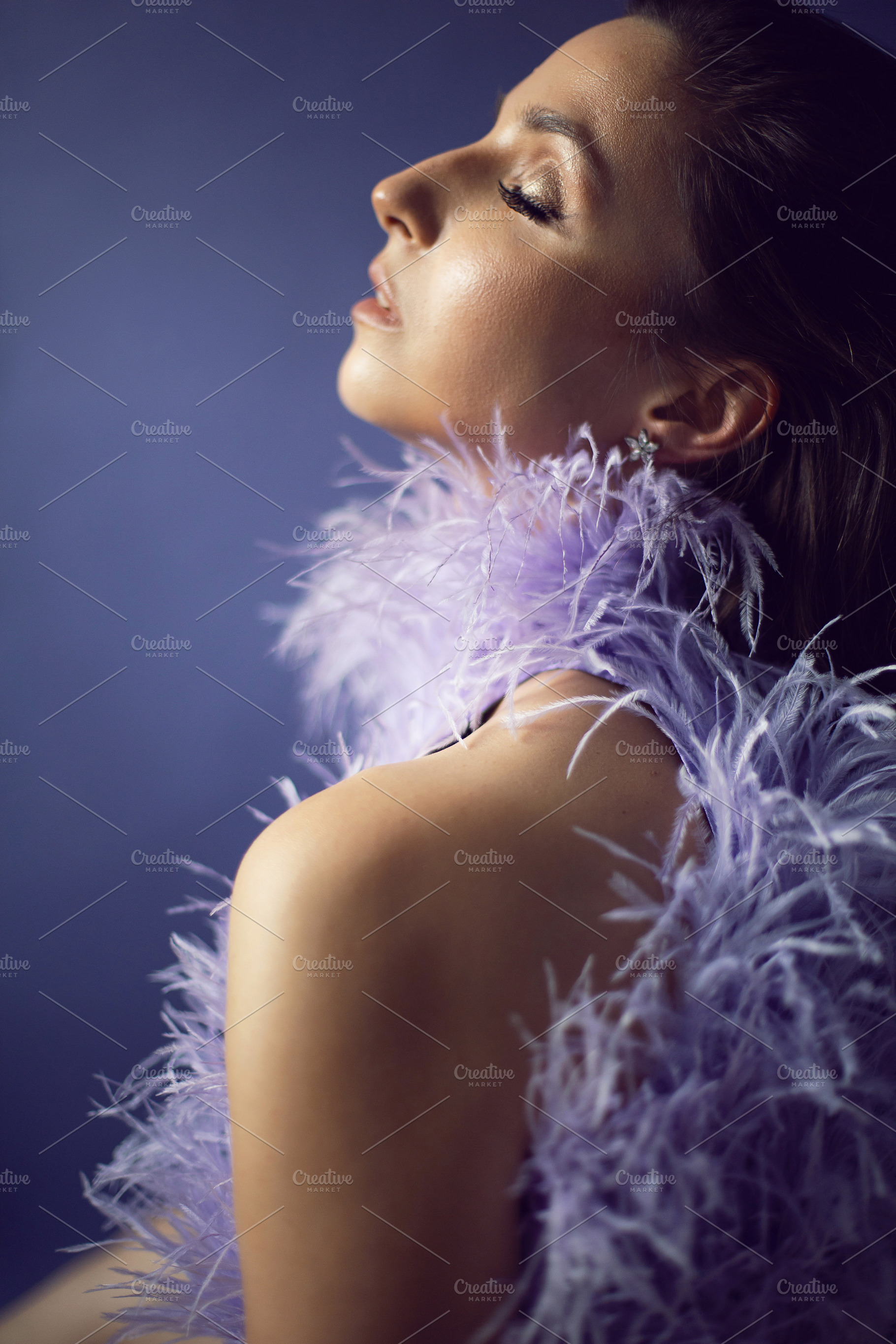 portrait woman in an evening purple dress with feathers stands in the backgroun, a Person Photo by SaulichPhoto