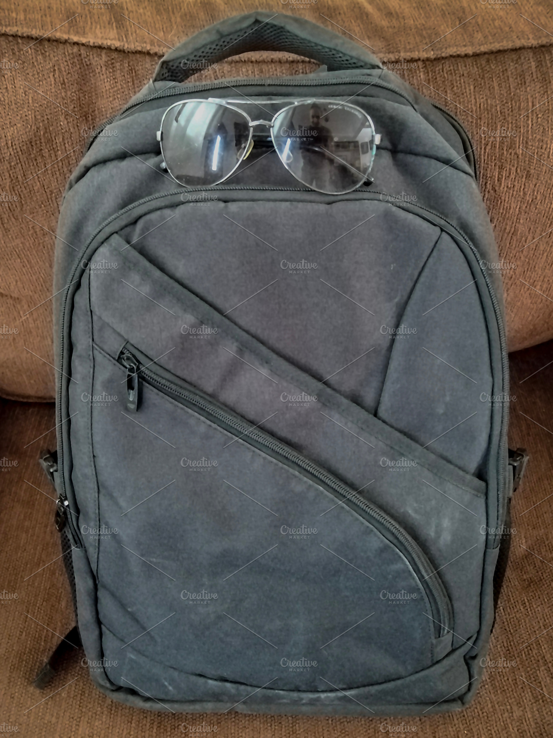 Backpack with sunglasses resting on couch, a Holiday Photo by DanFLCreativo
