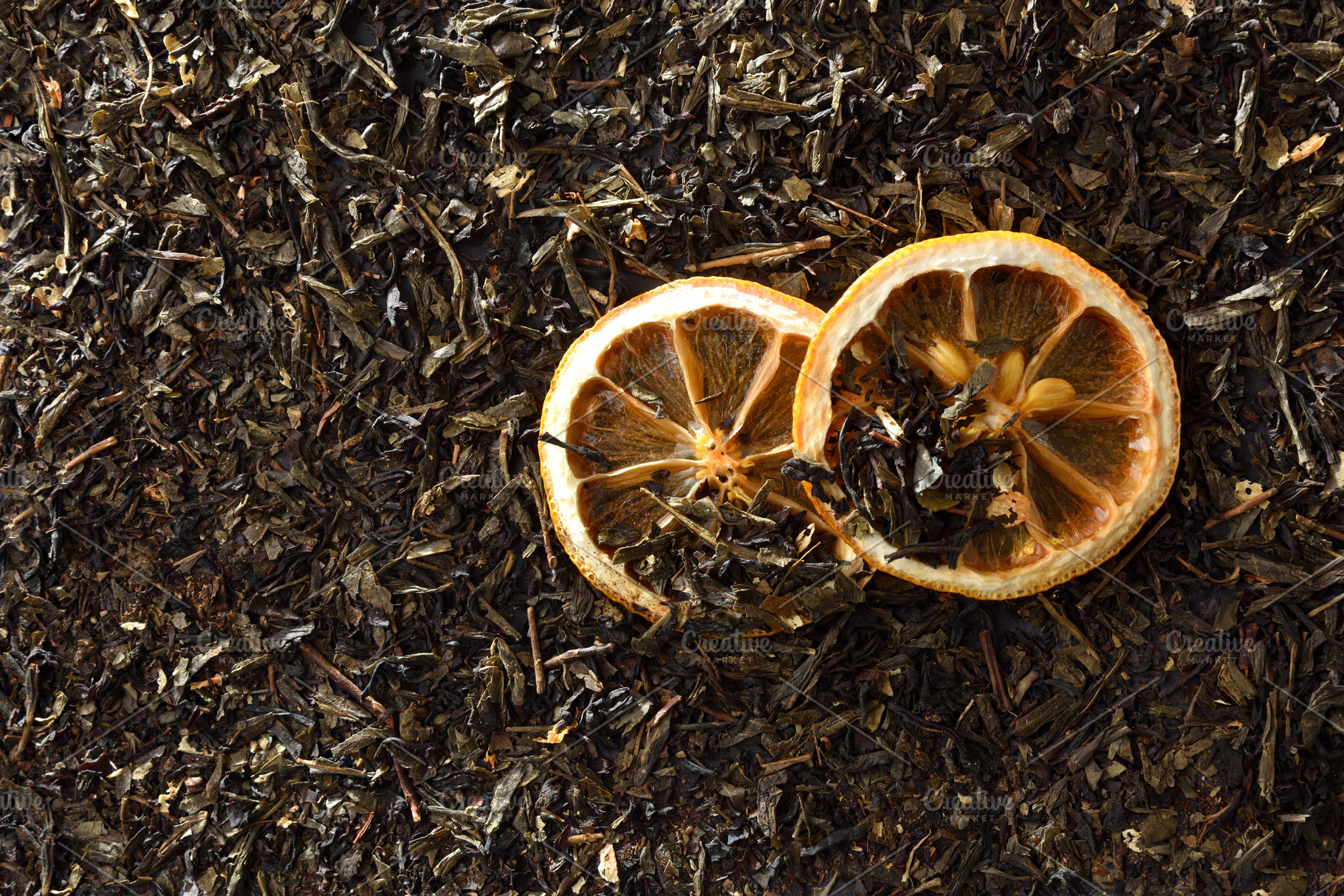 Dehydrated orange slices on a background of dried tea leaves, a Food & Drink Photo by Davizro's Market