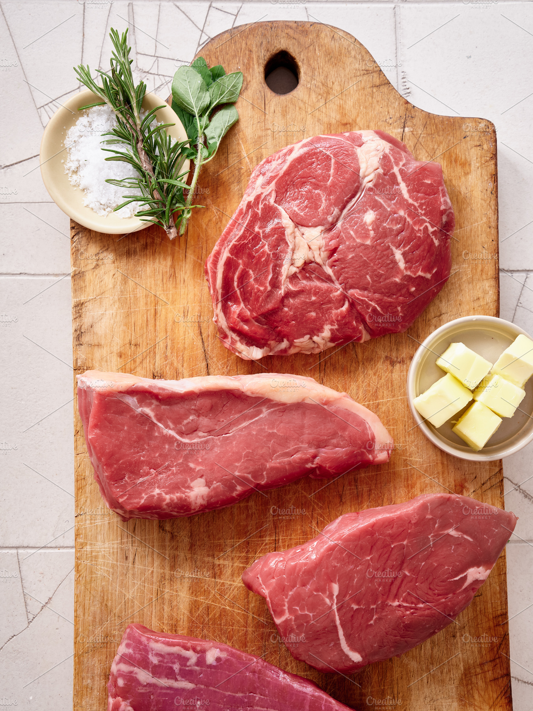 Raw rib-eye, roast beef, flank and rump steak on a wooden cutting board in a ki, a Food & Drink Photo by Asya Nurullina