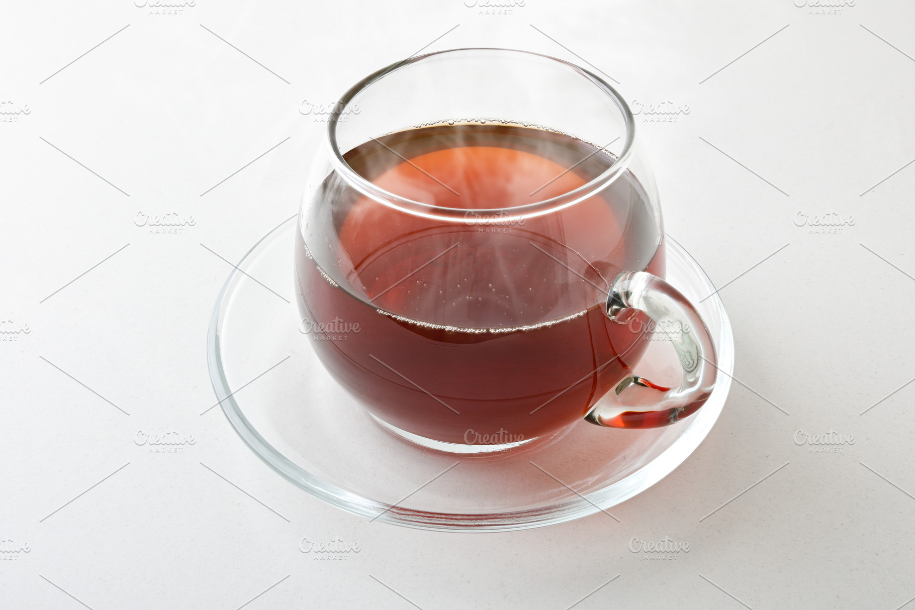 Hot infusion in a glass cup with saucer isolated, a Food & Drink Photo by Davizro's Market