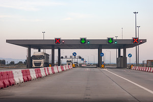Contemporary highway toll plaza with trucks and illuminated signals under a cle, a Transportation Photo by Ales Munt
