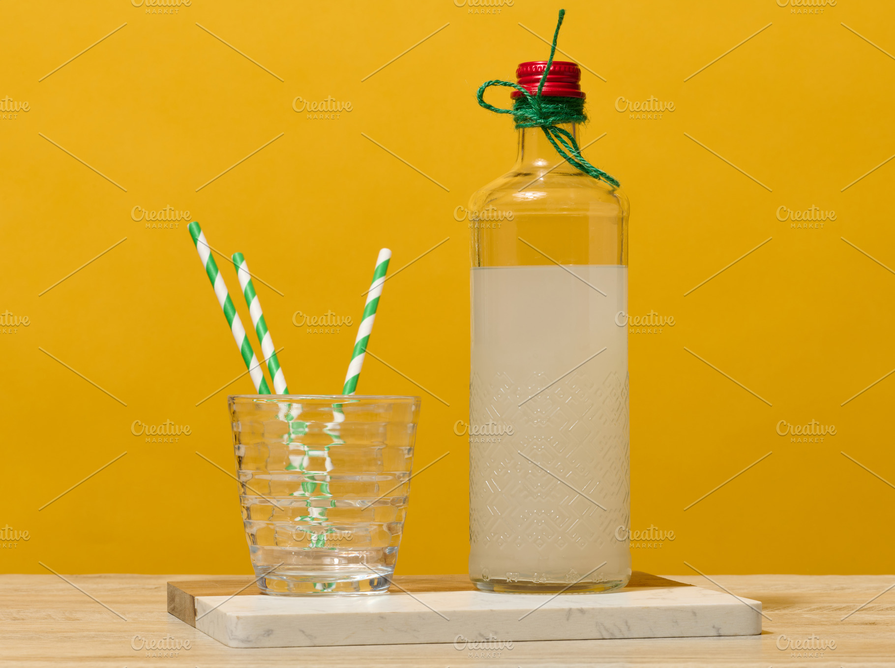 A transparent glass bottle of lemonade stands next to a faceted, a Food & Drink Photo by ndanko