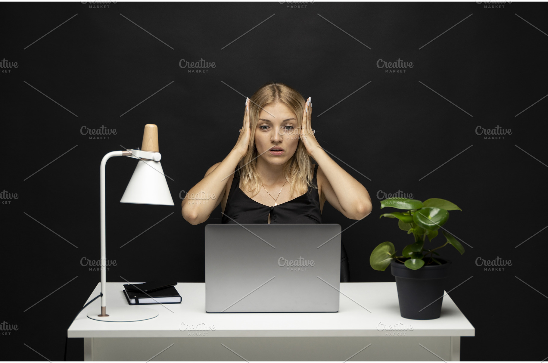 Shocked young woman at desk with, a Business Photo by volodymyrshtun13795