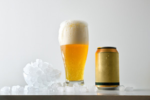 Foamy beer and can on table with ice cubes, a Food & Drink Photo by Davizro's Market