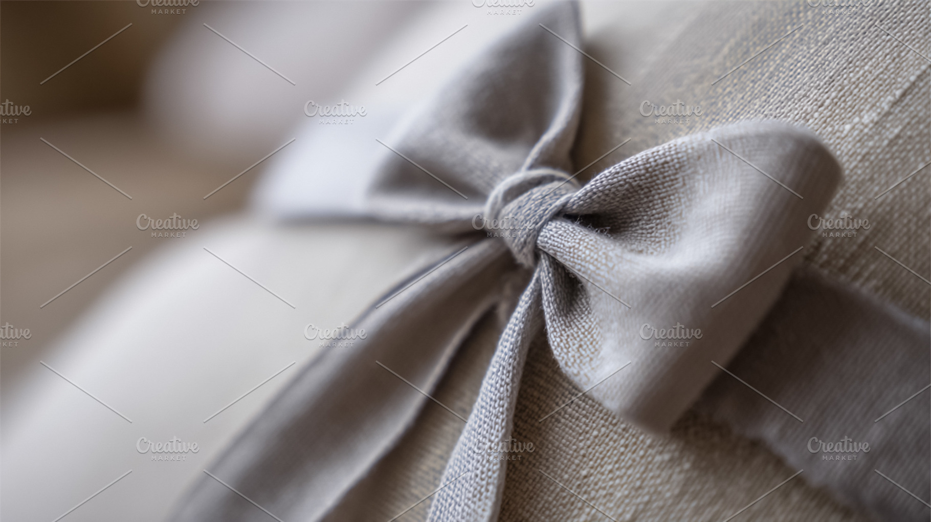 Gray linen bow detail on a pillow, showcasing soft fabric and te, a Photo by Studio ANNA