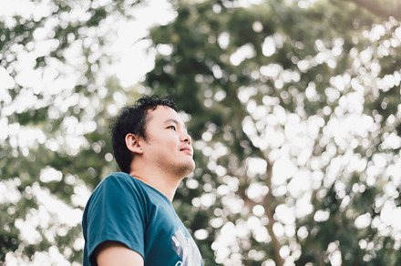 Asian man standing smiling happily under big tree in the public, a Person Photo by Ministocker