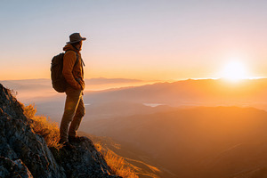 Person on cliff at sunrise overlooking misty valley, a Person Photo by AlyaAnd