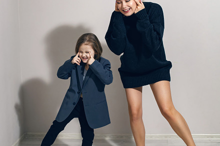 funny portrait of a fashionable girl child in a large gray jacket stands agains, a Person Photo by SaulichPhoto