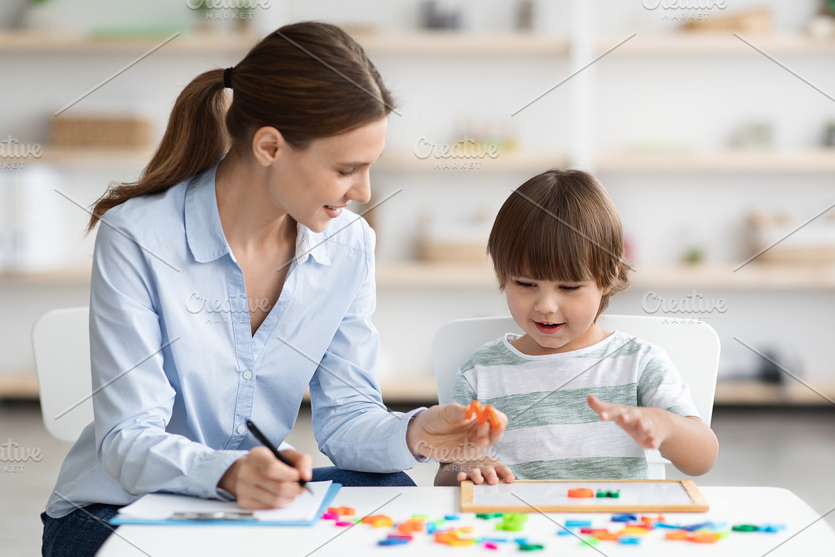 Professional woman specialist training with cute little boy, showing him oral e, a Photo by Prostock-Studio (Photo 2 of 2)