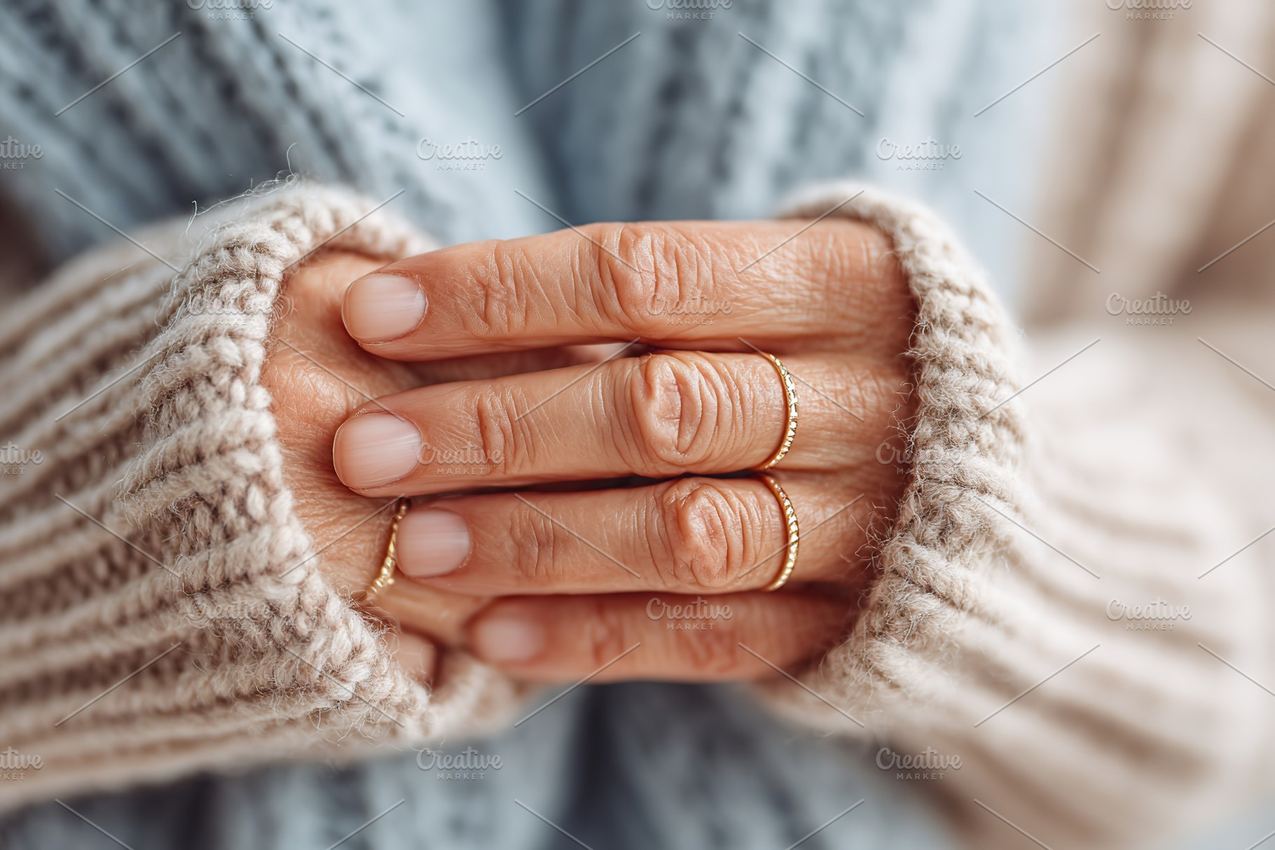 Hands adorned with delicate gold rings resting gently in a cozy knitted sweater, a Beauty & Fashion Photo by AlyaAnd