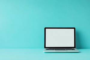 Open laptop computer sits on a blue, a Photo by Pavel_design