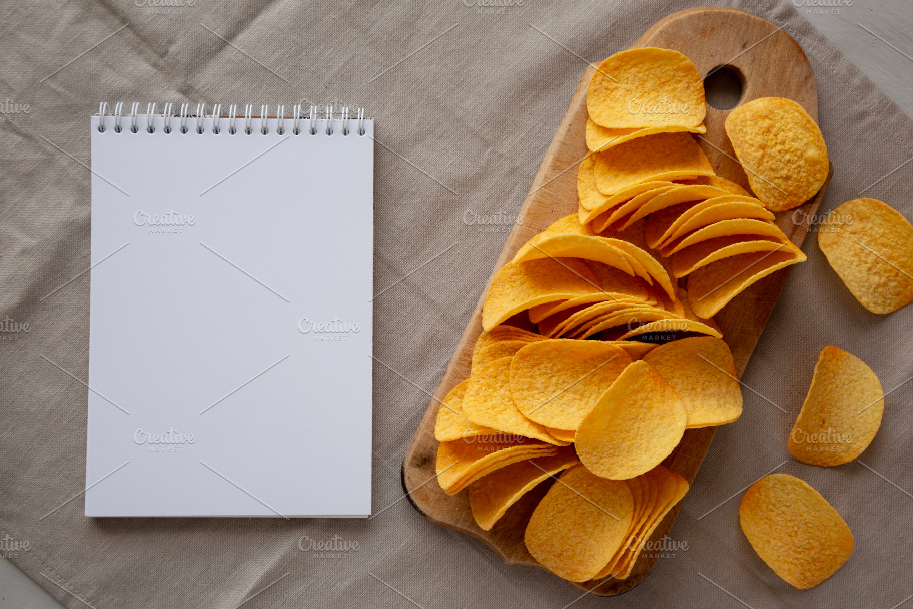 Bacon flavoured potato chips on a wooden board, blank notepad, t, a Food & Drink Photo by LiudmylaChuhunova
