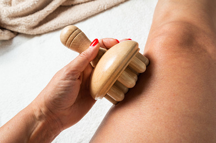 Hand holding a wooden massage roller during maderotherapy on the