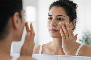 Woman applying cream to face for sum, a Photo by Dvoevnore photos