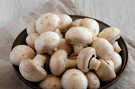 Raw White Champignon Mushrooms in a Bowl on a white wooden backg, a Food & Drink Photo by LiudmylaChuhunova