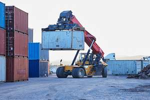 Logistics, cargo and forklift with container with stock for delivery in an industrial port. Ecommerce worker working with transportation of manufacturing product with a crane at an outdoor warehouse, a Photo by Peopleimages.com