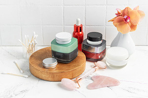 Skincare product bottles with jade roller and orchid, a Beauty & Fashion Photo by Olena Rudo