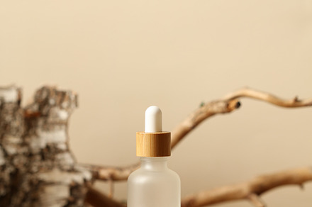 Transparent cosmetic dropper bottle on wooden podium. Natural forest cosmetic c, a Beauty & Fashion Photo by photoguns