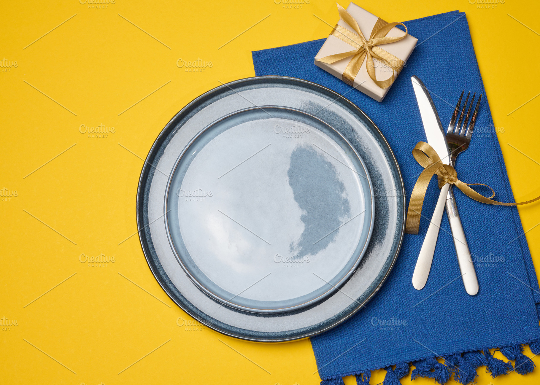 Festive table setting on a yellow background with a gray plate a, a Food & Drink Photo by ndanko